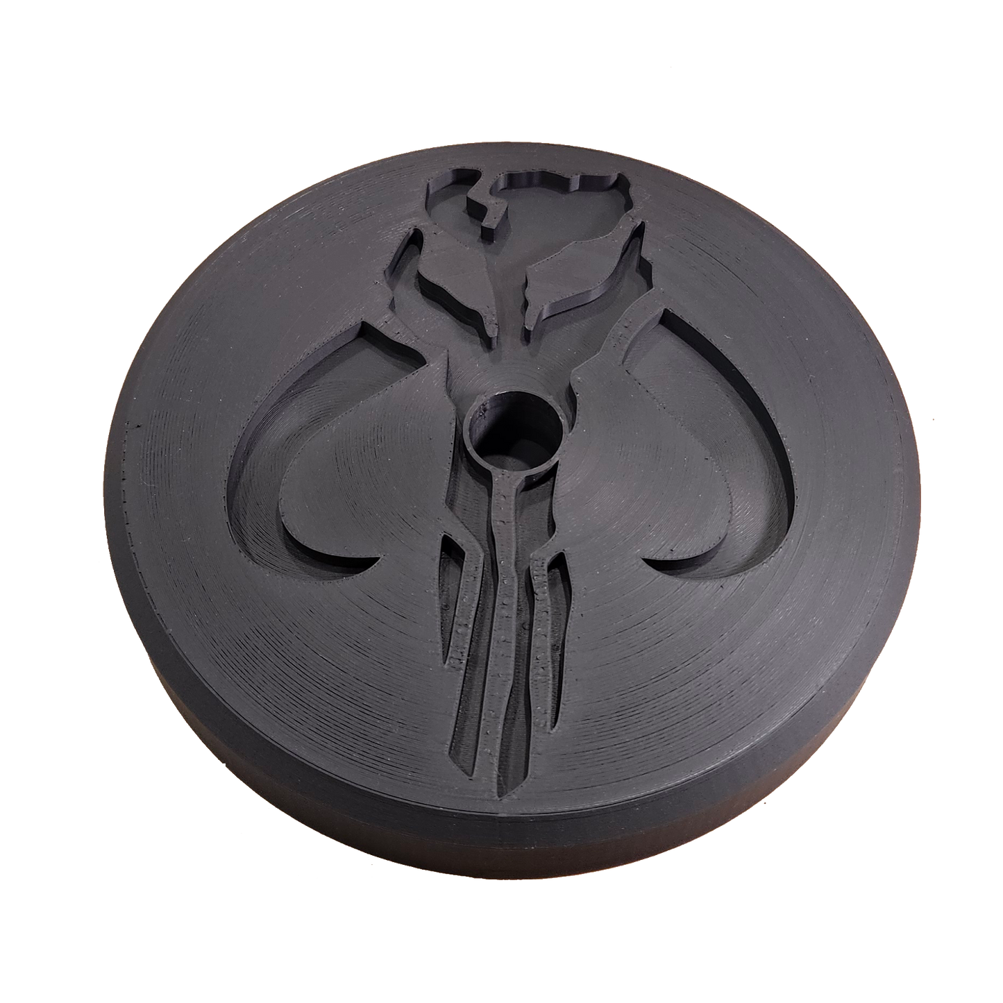 Black circular object with a central hole and intricate design on a white background