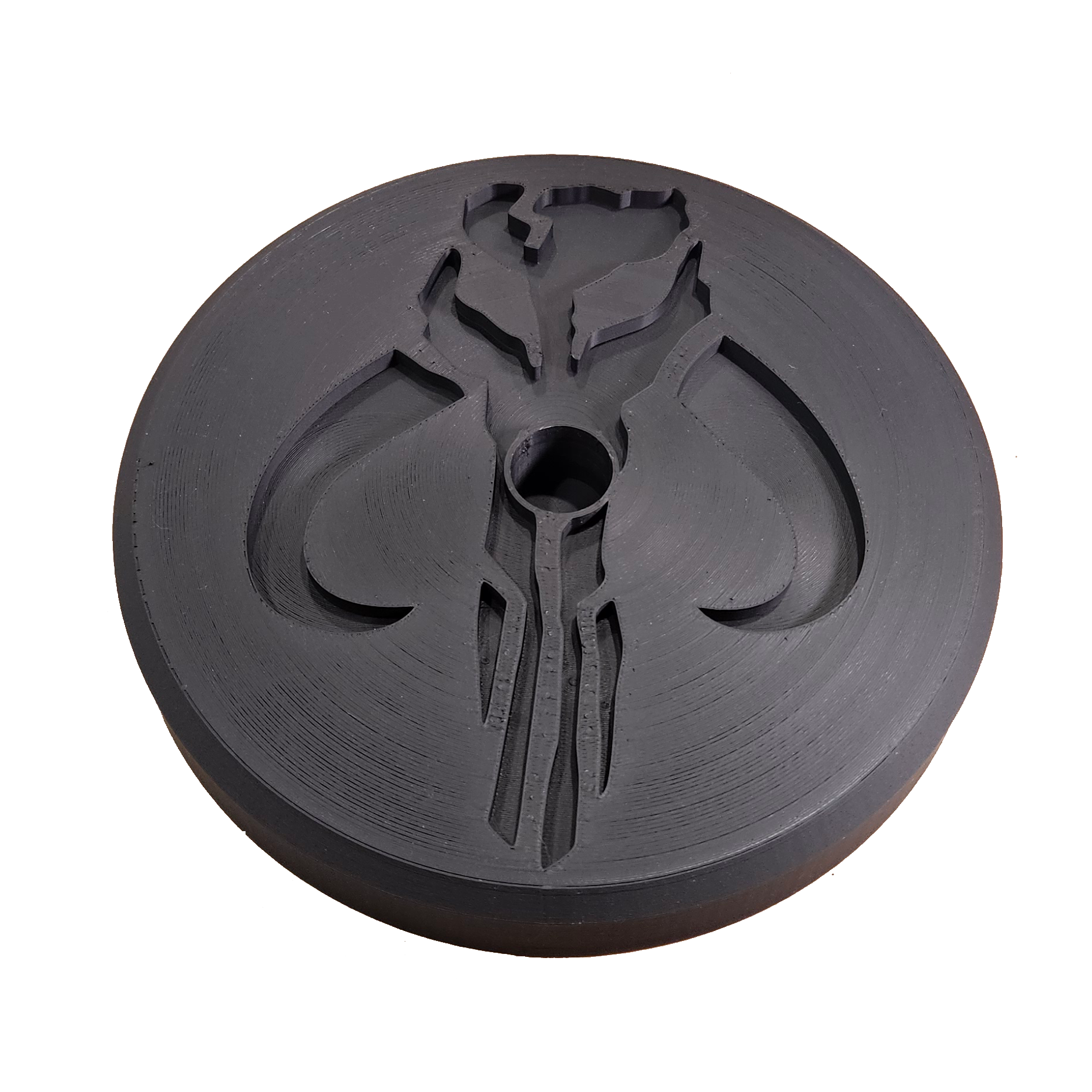 Black circular object with a central hole and intricate design on a white background